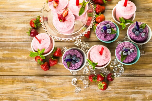 Paletas heladas caseras de arándanos y fresas en vasos de plástico.