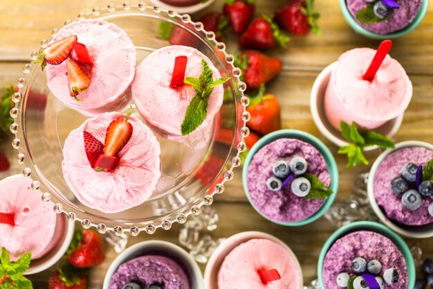 Paletas heladas caseras de arándanos y fresas en vasos de plástico.