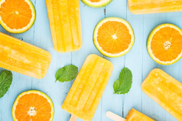 Paletas heladas caseras con naranjas en una madera azul