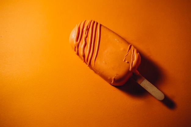 Paletas de helado de chocolate con hojuelas de almendras sobre fondo naranja