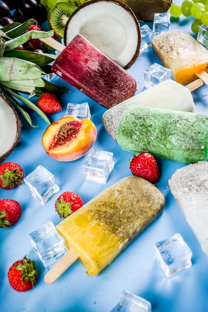 Foto paletas de helado tropical con semillas de chía y jugos de frutas: piña, naranja, mango, plátano, kiwi, coco, uvas, durazno, fresa