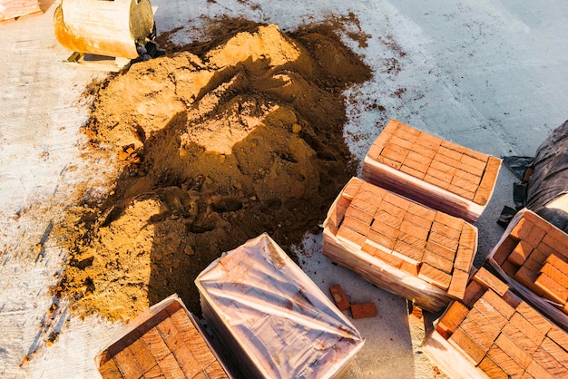 Paletas con ladrillos cerámicos rojos en el techo de un edificio en construcción Trabajos preparatorios para la colocación de ladrillos Vista superior del sitio de construcción