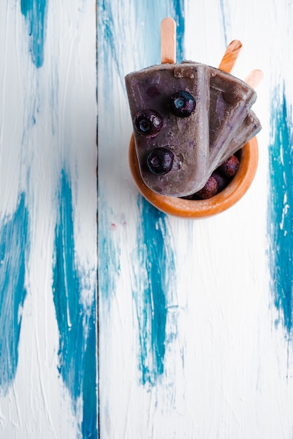 Paletas de leche de coco de arándanos veganos caseros sobre fondo de madera fresca