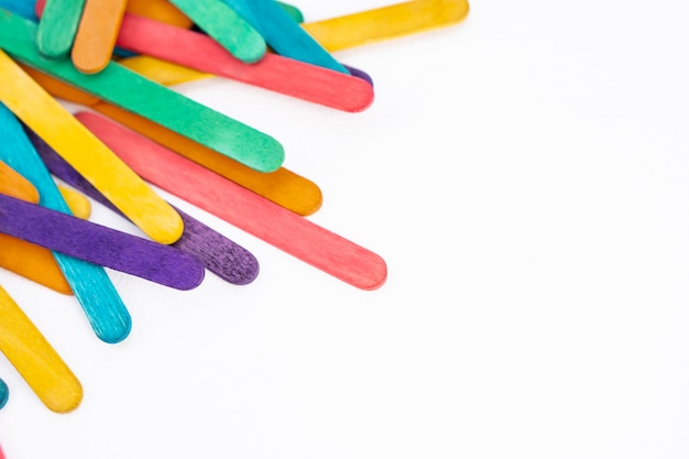 Paletas de madera de colores del arco iris sobre papel blanco