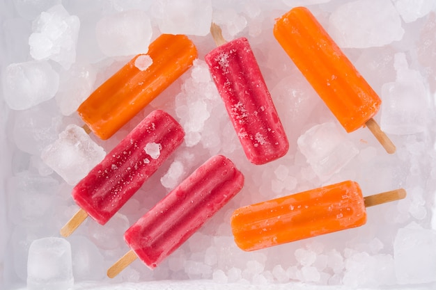 Paletas de naranja y fresa en cubitos de hielo, vista superior