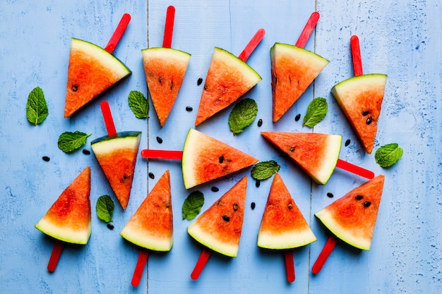 Paletas de rebanada de sandía sobre un fondo de madera rústica azul