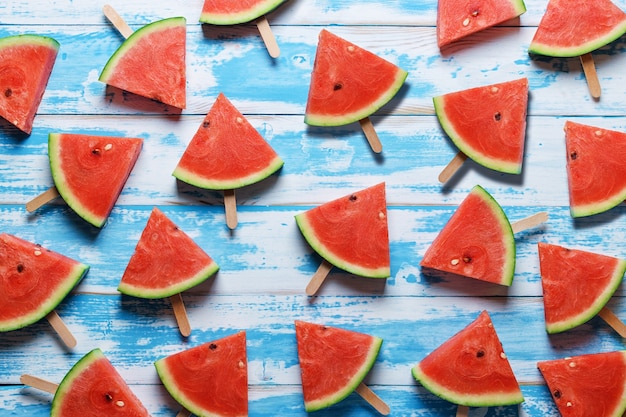 Paletas de rodajas de sandía sobre un fondo de madera azul