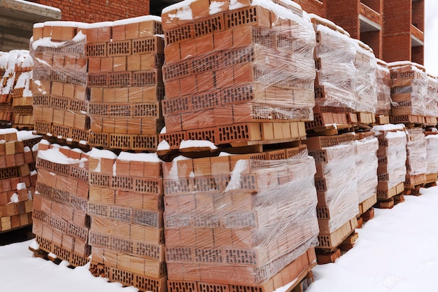 Paletes de tijolos fecham no canteiro de obras de inverno Bloco de tijolos na construção de casas de tijolos