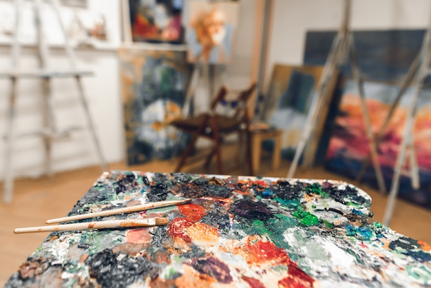 Palette von Ölfarben und Pinseln auf dem Hintergrund eines Studios