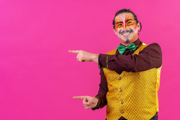 Palhaço com maquiagem facial branca mostrando um espaço vazio no fundo rosa anunciando algo