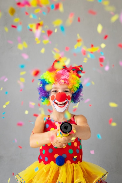 Palhaço de criança engraçada com poppers de festa. Criança feliz brincando em casa. Conceito do Dia da Mentira de 1º de abril