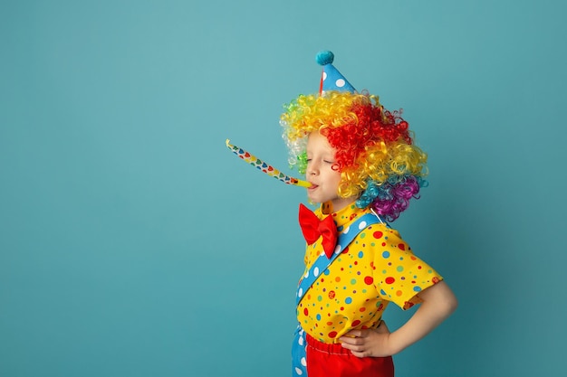 Palhaço de criança engraçada contra fundo azul Criança feliz brincando com decoração festiva 1º de abril dia da mentira