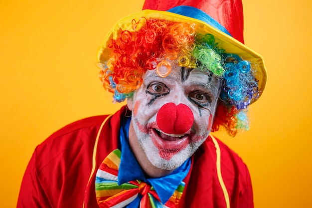 Palhaço feliz em traje colorido contra um fundo amarelo vibrante
