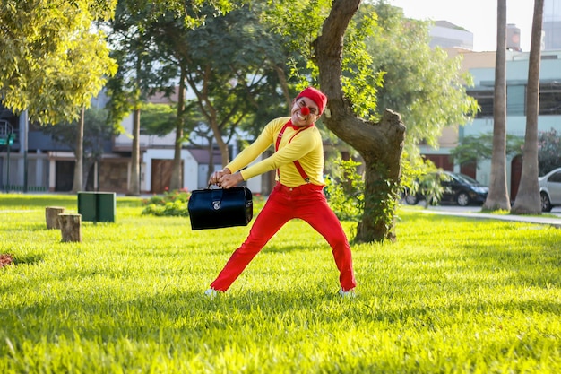 Palhaço tentando mover uma mala em um parque