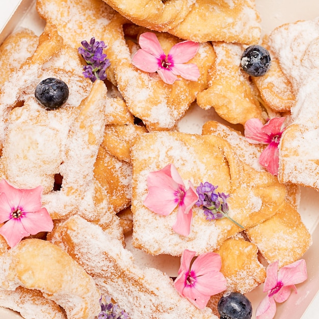 Palhas finas crocantes e quebradiças, biscoitos salpicados de açúcar de confeiteiro decorado com flores. cozimento caseiro. exceto de padaria e servir comida estética bonita. vida doce. foto de close-up