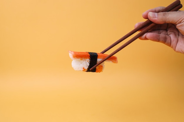 Foto los palillos de comer sostienen kani sushi o palillo de cangrejo en la parte superior del arroz rap por algas comida tradicional japonesa