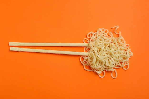 Foto palillos con fideos cocidos en naranja