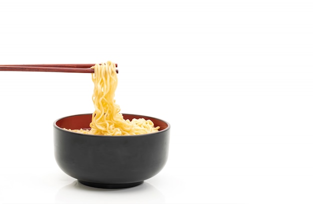 Palillos de fideos en un recipiente negro sobre un fondo blanco.