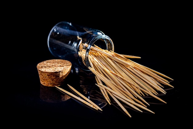 Palillos de madera de bambú en tarro de cristal copa de vino en palillos de cubo sobre fondo negro vista frontal palillos caídos del lugar de la mano para el texto