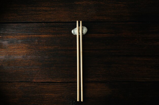 Foto palillos de madera para comida asiática china sobre fondo de madera oscura y piedra