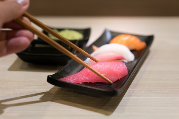 Palillos con sushi de atún crudo de Japón y sushi fresco mezclado en un plato negro