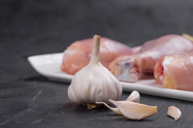 Palillos de tambor de pollo crudo dispuestos en vajilla blanca