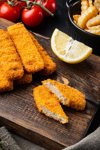 Palito de peixe frito ou batata frita peixe com molho definido em uma tábua de madeira