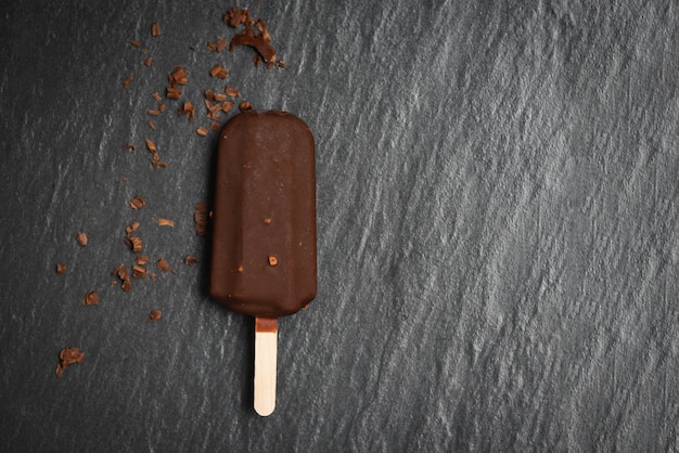 Foto palito de helado con almendras y nueces sobre palitos de chocolate negro helado cubierto