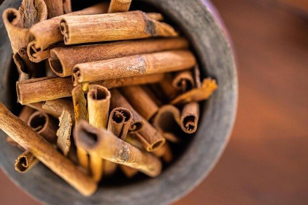 Palitos de canela aromáticos en un tazón sobre una mesa de madera marrón, primer plano. Fondo de pantalla de ingredientes de alimentos artísticos