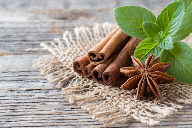 Palitos de canela y estrellas de anís con menta sobre tabla.