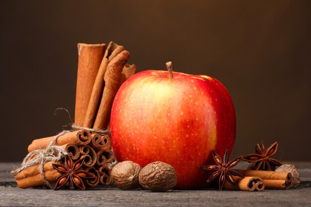 Palitos de canela, manzana roja, nuez moscada y anís en mesa de madera