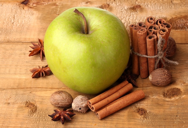 Palitos de canela, manzana verde, nuez moscada y anís en mesa de madera