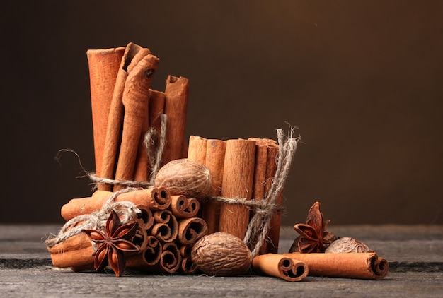 Palitos de canela, nuez moscada y anís en la mesa de madera sobre fondo marrón