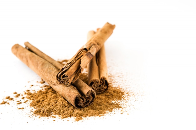 Palitos de canela y polvo aislado en blanco