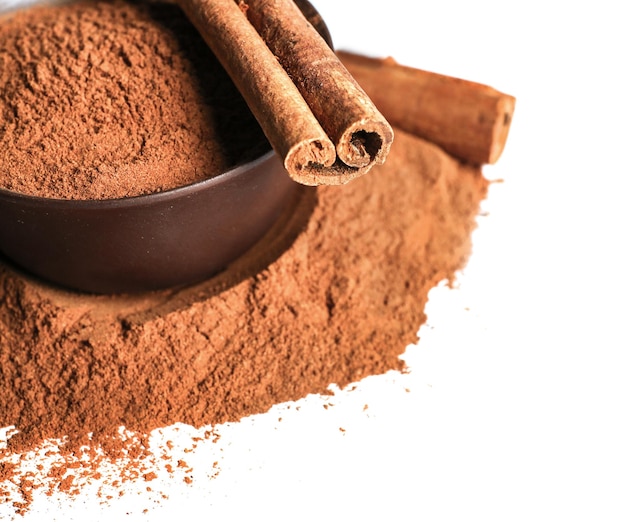 Palitos de canela y polvo en cuenco de cerámica aislado en primer plano blanco