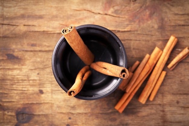 Palitos de canela en taza sobre fondo de madera vieja. Vista superior