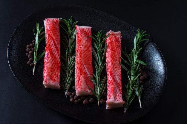 Palitos de cangrejo en un plato negro decoración de un plato de restaurante para delicias de mariscos