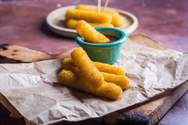 Foto palitos de mussarela revestidos com molho picante.