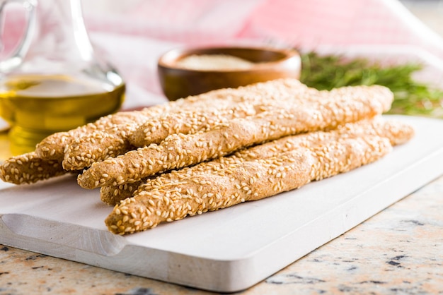 Palitos de pão grissini italiano com sementes de gergelim na tábua de cortar branca