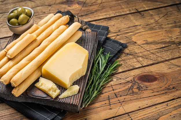 Palitos de pão grissini tradicional aperitivo italiano na placa de madeira com azeitonas e queijo parmesão Bakground de madeira Vista superior Copiar espaço