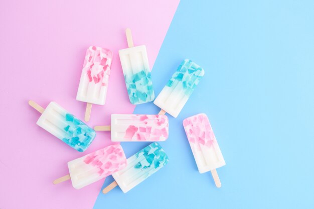 Palitos de sorvete caseiros, picolé, gelo pop ou freezer pop em fundo de cores pastel azul e rosa