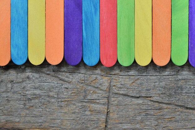 Palitos de helado de colores sobre fondo de madera con texto EDUCACIÓN EN EL HOGAR EN LÍNEA