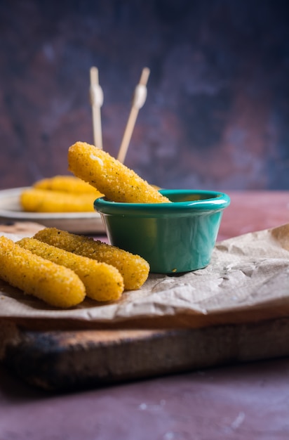 Foto palitos de mozzarella recubiertos con salsa picante.