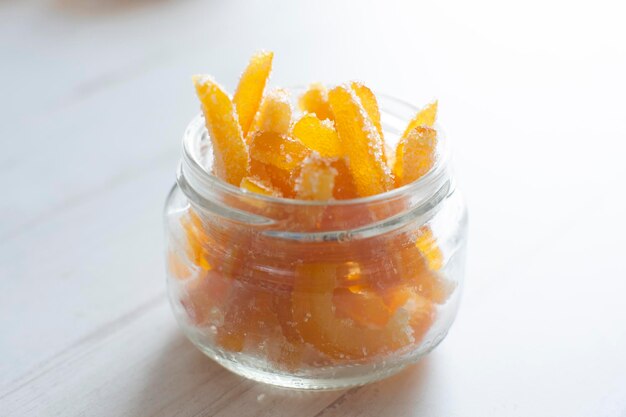 Palitos de naranja confitada en azúcar servidos en vaso.