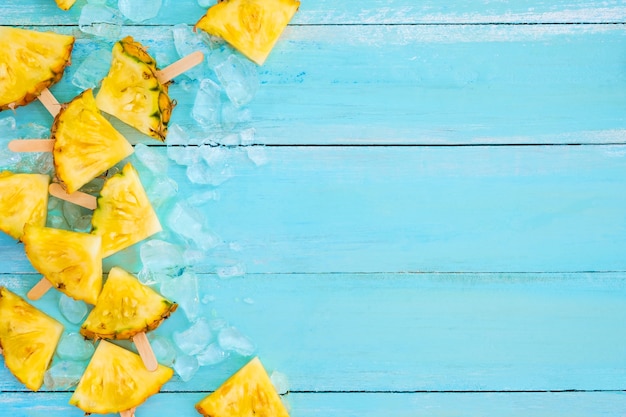 Palitos de paleta de piña con hielo en color azul tablón de madera