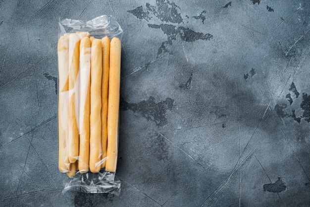 Palitos de pan, con aceite de oliva, sobre fondo gris, plano con espacio para copiar texto