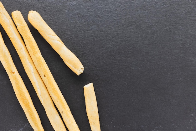 Palitos de pan Grissini frescos italianos servidos sobre fondo negro Pan horneado seco con trozos de aceituna