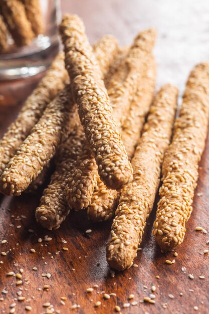 Palitos de pan grissini Palitos de pan con semillas de sésamo sobre mesa de madera