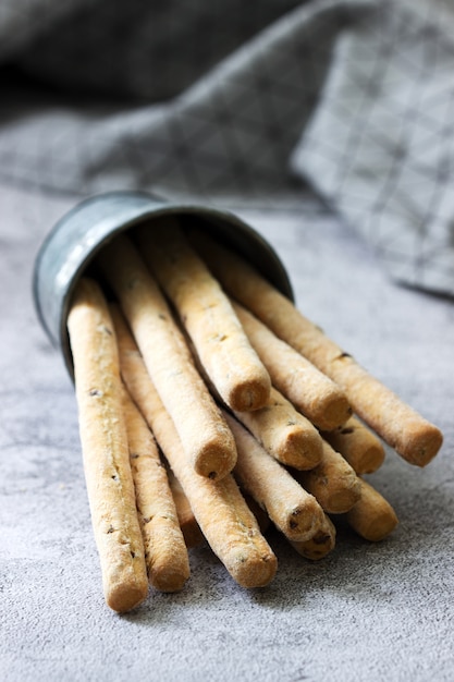 Palitos de pan italiano tradicional grissini con semillas de lino sobre una superficie gris