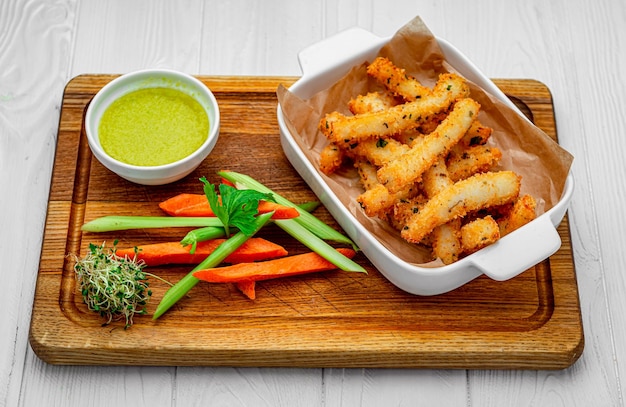 Palitos de pescado con verduras frescas en una tabla de madera